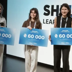 Three young women stand with signs announcing "SHELEADS LEARN, LAUNCH, LEAD" and "€60 000".