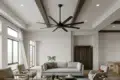 Bright open-plan living room with a gray sofa, armchairs, large windows, a ceiling fan, wood beams, and a dining area.