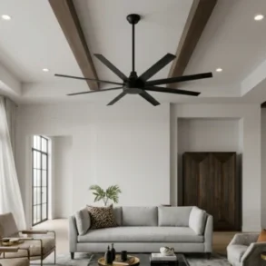 Bright open-plan living room with a gray sofa, armchairs, large windows, a ceiling fan, wood beams, and a dining area.