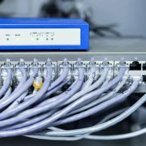 Network equipment with numerous Ethernet cables plugged into a 24-port switch beneath a blue wireless router.