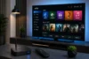 IPTV streaming setup with a smart TV displaying news, sports, movies, kids, and music categories, plus a set-top box and remote on a living room table.