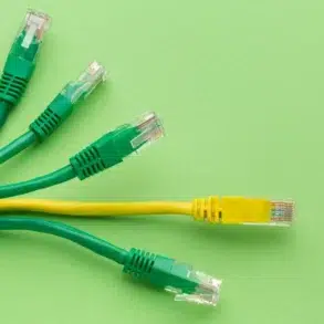 Green and yellow Ethernet cables with transparent RJ45 connectors arranged on a bright green background.