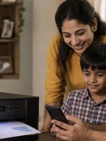 Smiling mother, father, and son gather around a smartphone beside a home printer with a document emerging, conveying family warmth and connection.