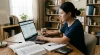 A dedicated student focused on studying for CPA exam task-based simulations, working on a laptop with textbooks, a calculator, and notes spread across a wooden desk.