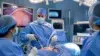 Surgeon and masked medical team perform minimally invasive surgery in a brightly lit operating room, with monitors showing the procedure; focused, clinical atmosphere.