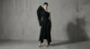 Model wearing a sculptural asymmetric black garment in a minimal studio setting