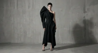 Model wearing a sculptural asymmetric black garment in a minimal studio setting